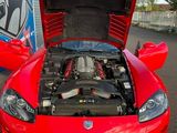 a red sports car with its hood open in a parking lot