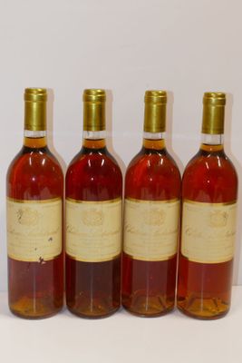 quatre bouteilles de vin sont alignées sur une surface blanche