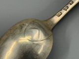 une cuillère en argent avec un manche en métal posée sur une table