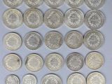 a close up of a pile of silver coins on a white surface