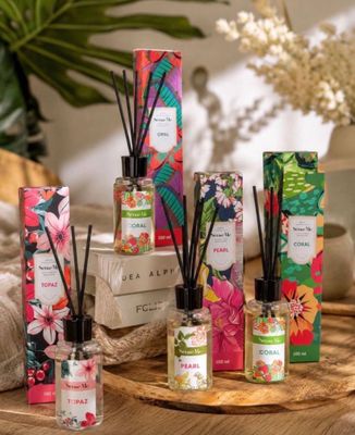an assortment of reeds and candles on a table with flowers