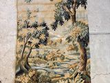 une vieille tapisserie accrochée au mur, représentant une rivière et des arbres