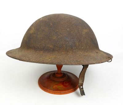 un vieux casque posé sur un support en bois, sur fond blanc