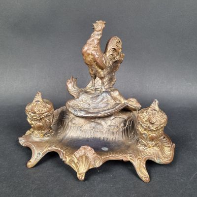 a statue of a rooster sitting on top of a bowl