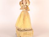 a doll that is dressed in a yellow dress and holding an umbrella