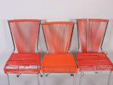three orange chairs sitting next to each other on a white surface