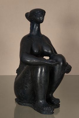 statue d'une femme assise sur une table en verre, les mains posées sur les genoux