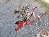 a red plow sitting on the ground next to a piece of metal
