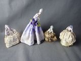 four porcelain figurines of women in dresses and hats on a gray background