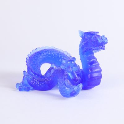 une figurine de dragon bleu posée sur une surface blanche