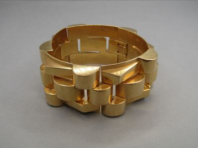 un bracelet en or posé sur une table, sur fond gris