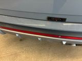 the rear end of a silver car with a sticker on it