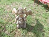 a statue of a child holding a book in the grass