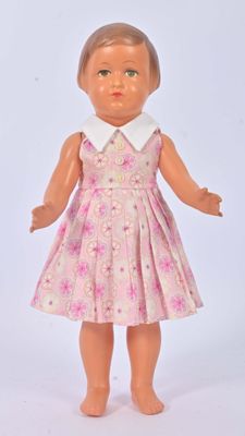 une poupée qui porte une robe rose et un col blanc