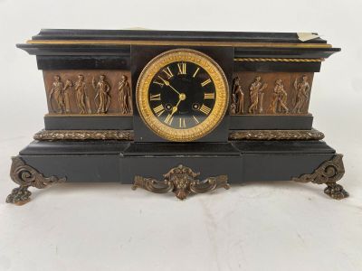 une horloge noire et dorée ornée de personnages