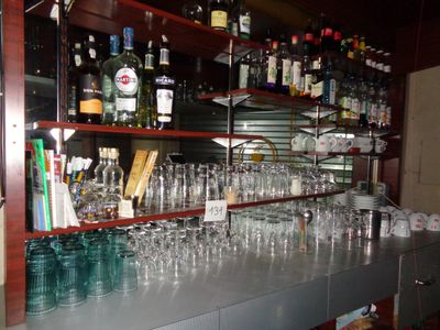 des bouteilles et des verres posés sur une étagère dans un bar où se trouvent de nombreuses bouteilles