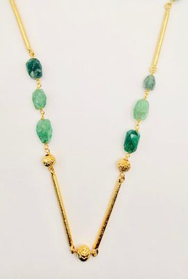 a gold necklace with green beads and a long chain