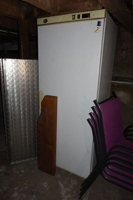 un réfrigérateur blanc au milieu d'une pièce, à côté d'une chaise violette