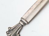 an antique silver plated knife with a decorative handle on a white surface