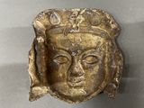 a gold plate with a face on it on a table