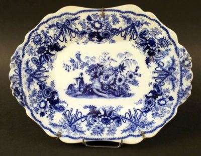 une vieille assiette bleue et blanche sur laquelle est représenté un homme dans un bateau