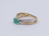 a close up of a ring with a green stone and diamonds
