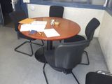 une table ronde avec quatre chaises et une valise posée dessus