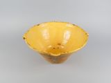 yellow ceramic bowl on a white surface with a gray background
