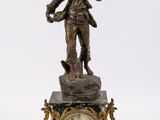 a statue of a man holding a clock on top of a table