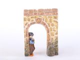 a figurine of a man standing in front of a stone arch