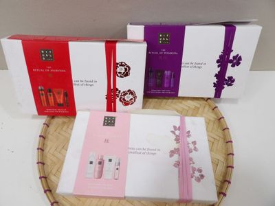 three boxes of perfume sitting on top of a wicker basket
