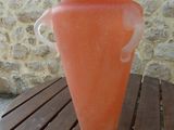 an orange vase sitting on a wooden table near a stone wall
