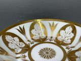 a gold and white bowl with leaves on it