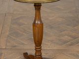 une vieille table en bois au plateau rond, posée sur un parquet
