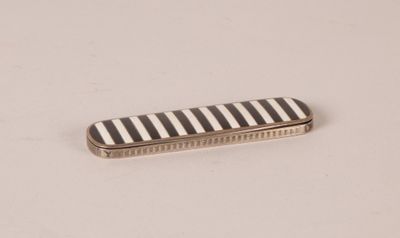 a close up of a black and white striped comb on a white surface