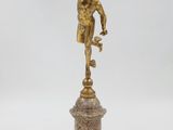une figurine antique en bronze représentant un garçon sur un socle