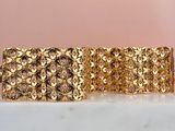 a close up of a gold bracelet on a marble surface