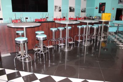 des tables et des tabourets dans un snack-bar au sol en damier