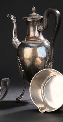 une théière en argent et une tasse en argent posées sur une table