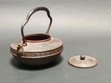 a small metal pot with a handle next to it