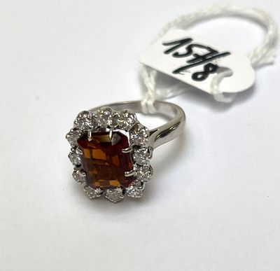 une photo d'une bague en argent sertie d'une pierre marron entourée de diamants blancs