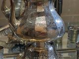 une théière en argent posée sur une table à côté d'un miroir