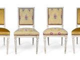 three white chairs with yellow upholstered cushions and a floral design