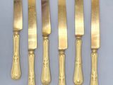 four gold plated knives and a knife holder on a table