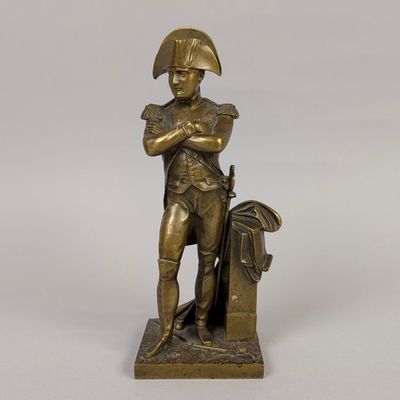 an antique bronze statue of a man with a hat and a bag