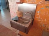 un lavabo dans des toilettes publiques, avec des graffitis sur les murs