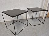 une paire de tables d'appoint en métal noir posées sur un sol en béton