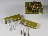 trois pièces d'argenterie dans une boîte verte posée sur une table blanche