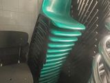 une pile de chaises vertes dans une pièce aux murs carrelés de blanc