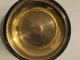 a gold plate on a white table with a black base